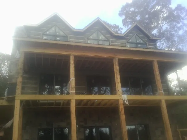Dormers and porch framing on a large log home under construction — Roof Coating work by our crew in Beloit
