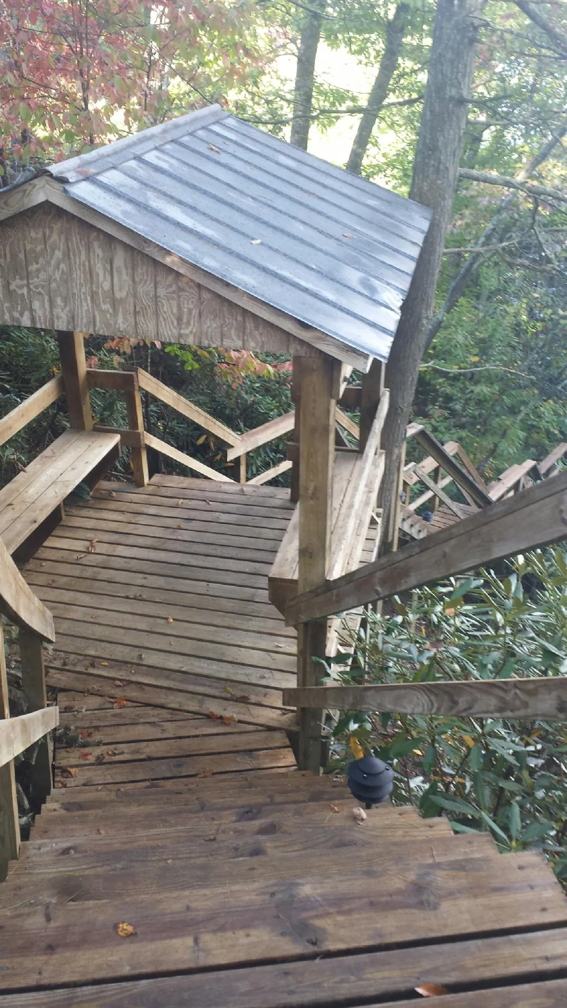 Metal roofed shelter over wooden steps on a wooded walkway — Skylight Repair & Installation work by our crew in Beloit