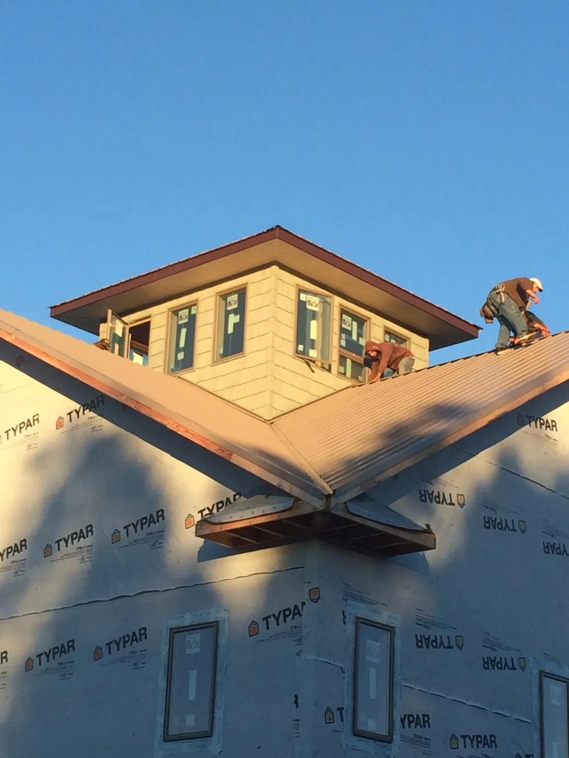 Roofers working around a rooftop cupola on a new metal roof at sunset — Roof Waterproofing in Beloit by Roofing Brothers